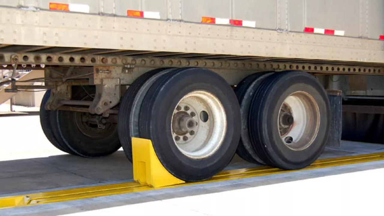 Rubber wheel chocks placed tightly against a trailer tire on a paved parking area